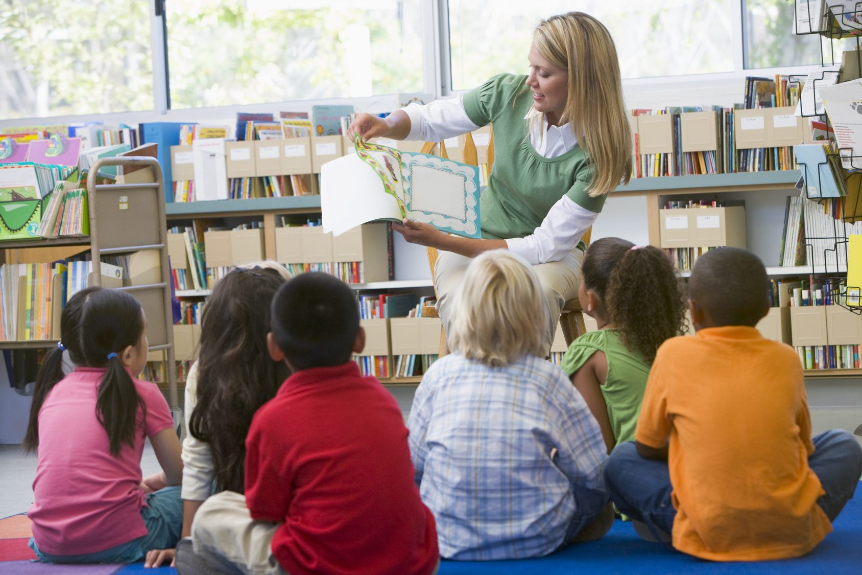 Kindergarten teacher reading to children in library Kindergarten teacher reading to children in library